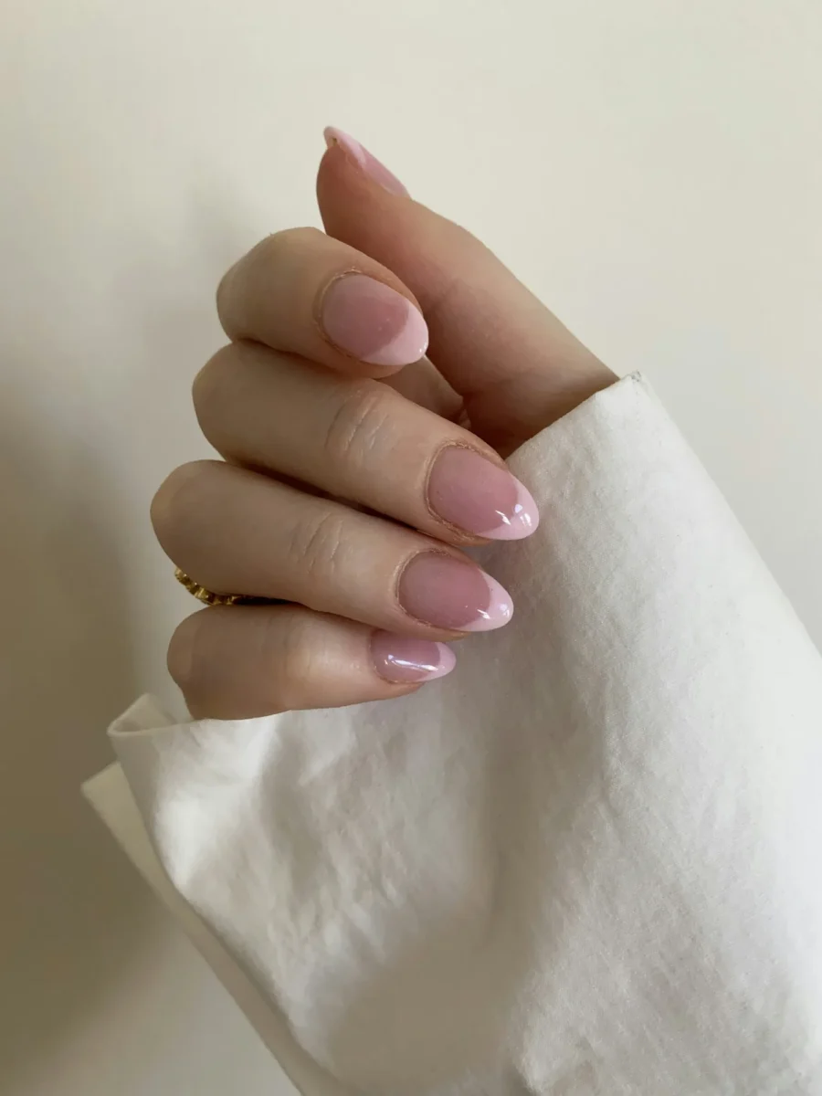 Soft nude ombre nails against a cream cloth