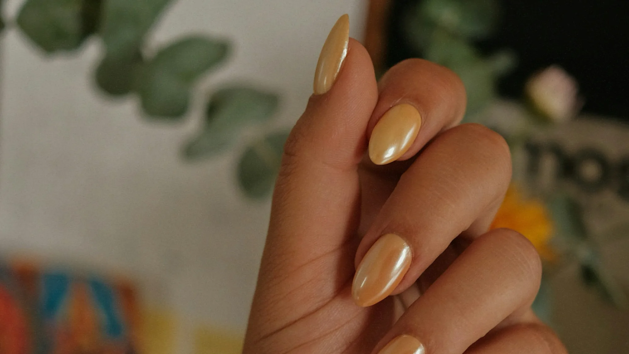 Hand with long almond nails in a gold chrome finish