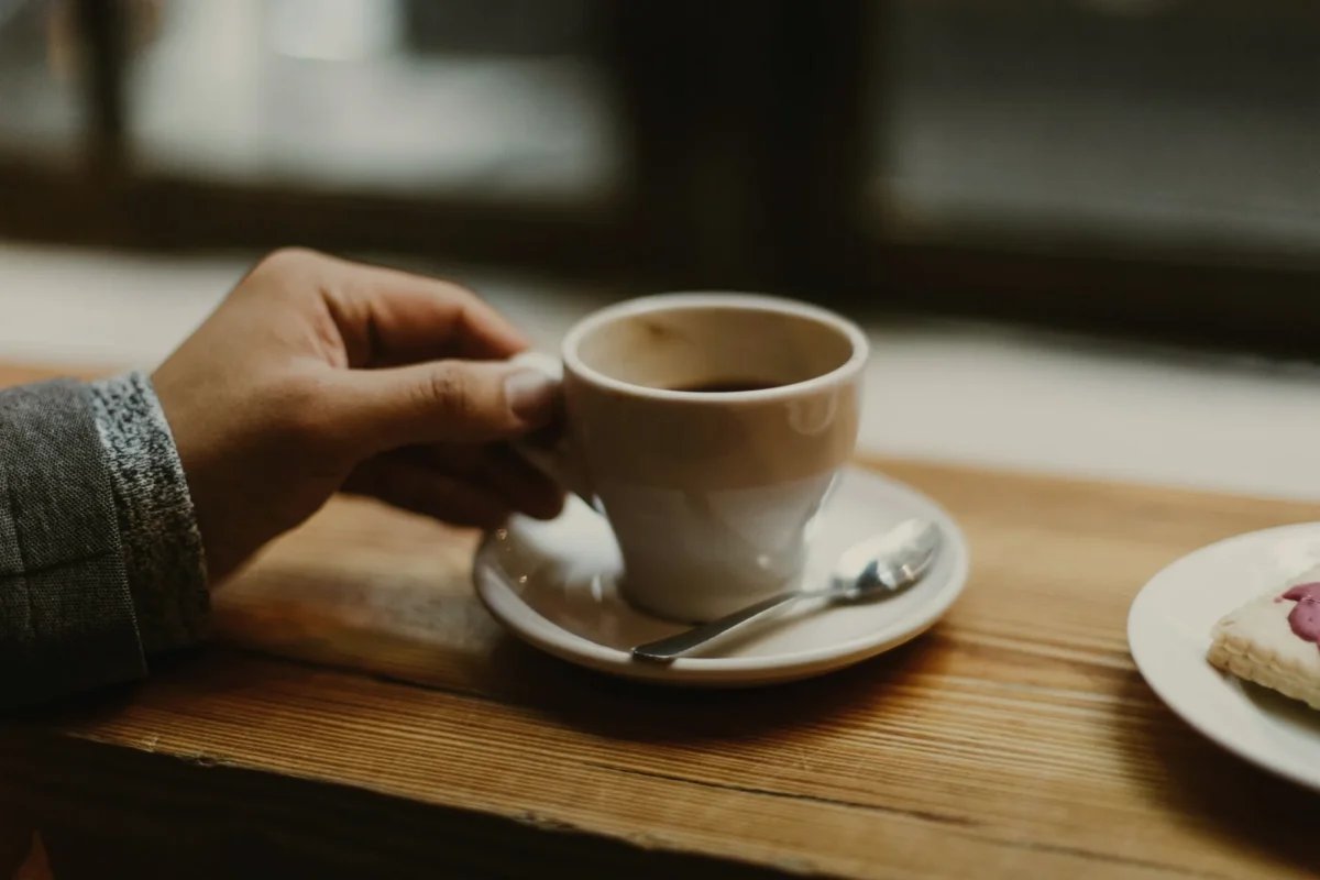 Hand holding a cup of coffee on a wooden table