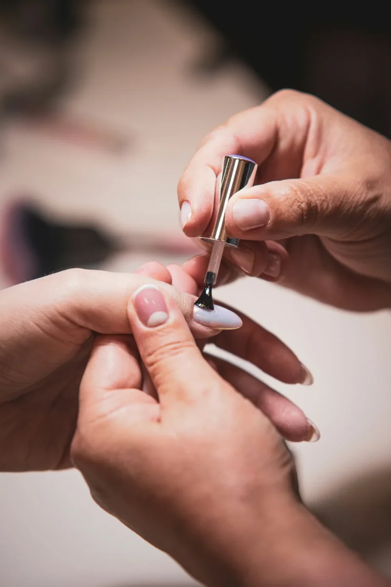 Nail technician brushing gel onto a client's nail