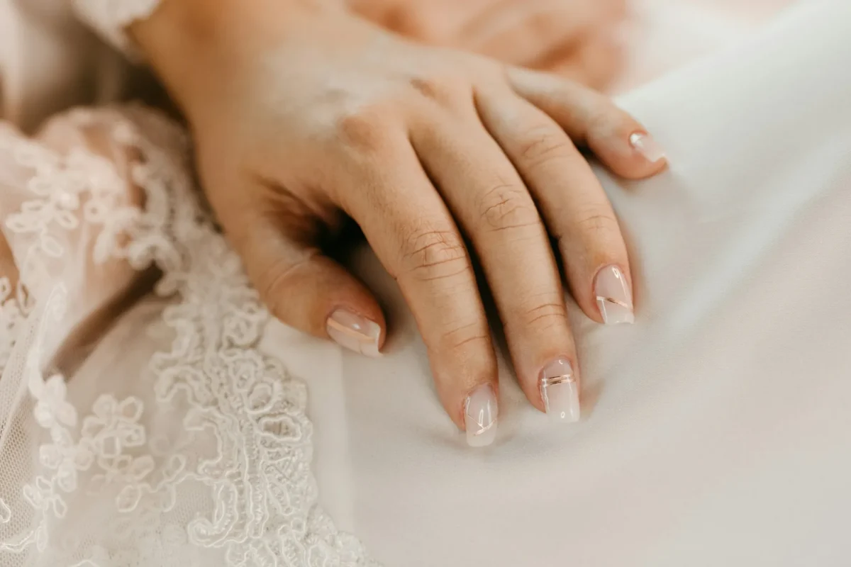 Hands with a soft French manicure resting on ivory lace