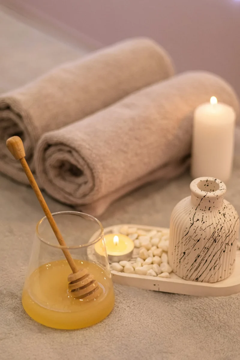Rolled towels with honey, a candle and a small vase for a sugar pedicure